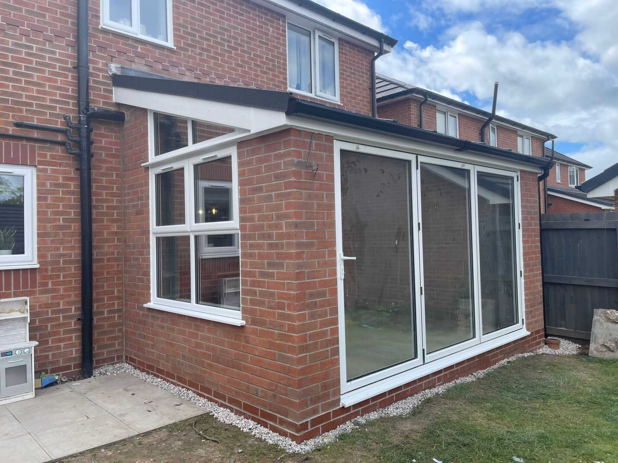 Newly completed house extension with large sliding glass doors and brick exterior, highlighting the quality construction work