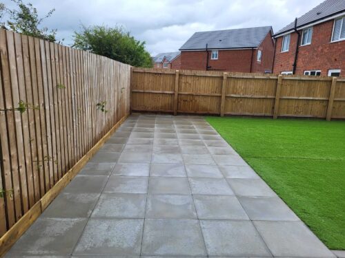 Newly installed flagged patio and artificial grass lawn in a residential backyard, showcasing professional landscaping and hardscaping